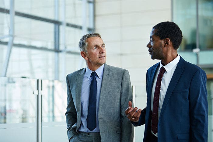 Shot of two businessmen walking together and talking together in the lobby of an office building